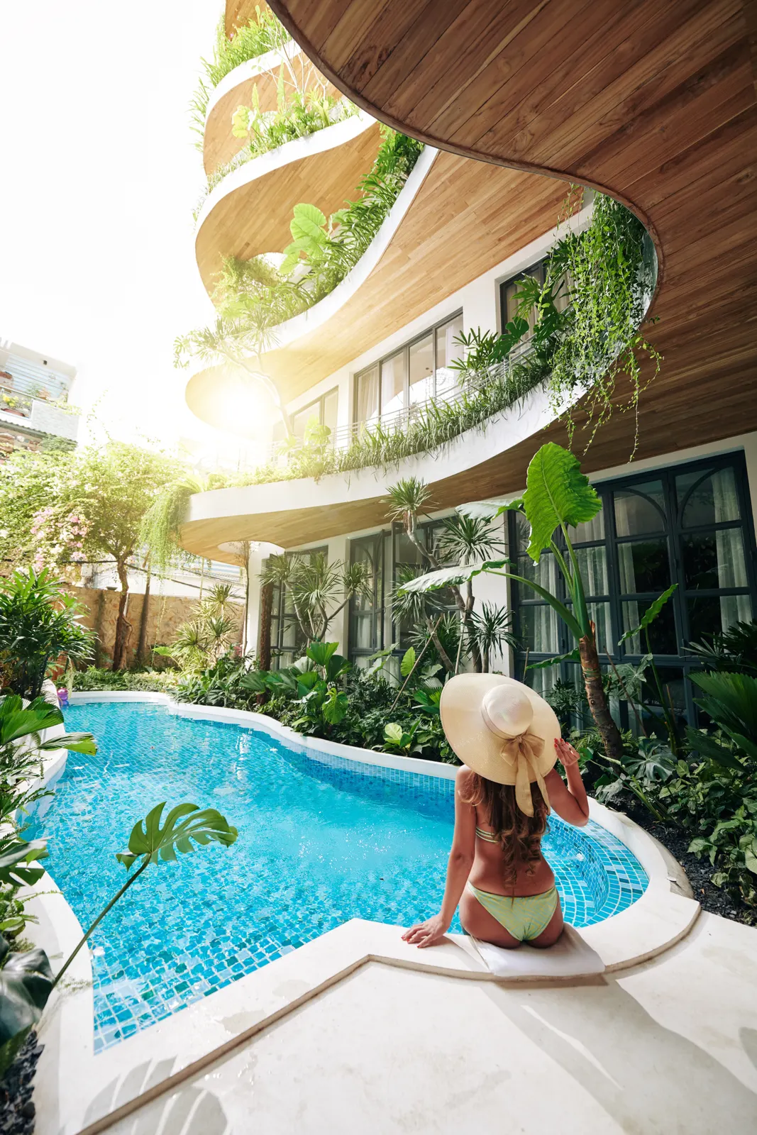 Mujer disfrutando una estancia en un hotel de lujo con piscina y entorno tropical