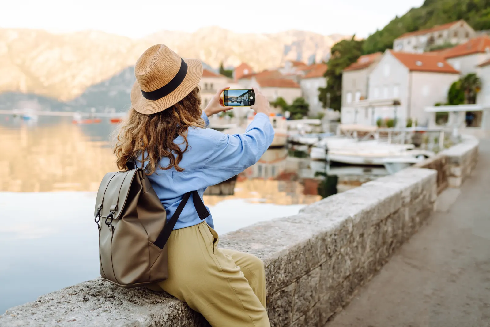 Mujer viajera fotografiando una ciudad costera durante un recorrido turístico