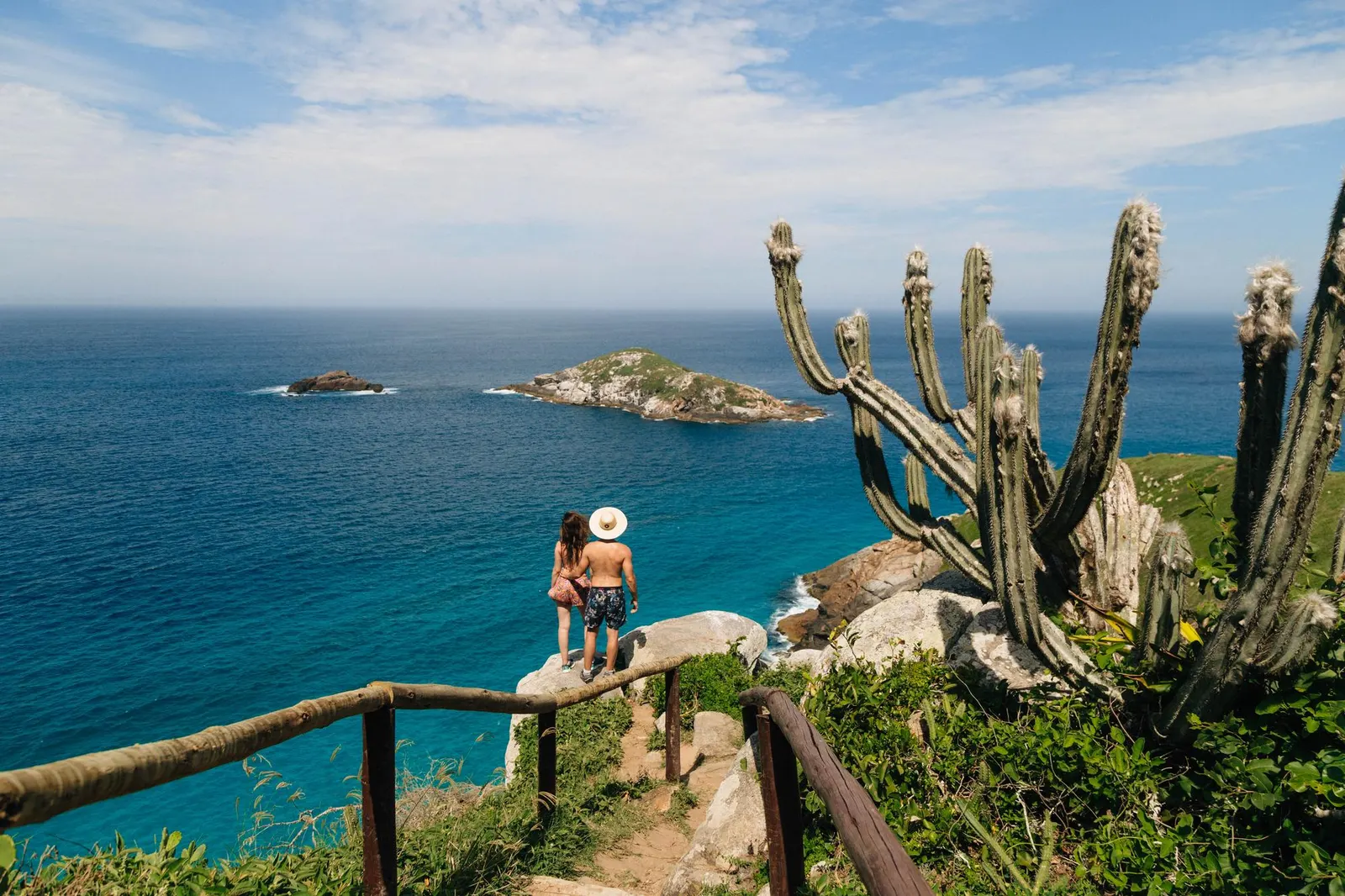 Pareja explorando un mirador frente al mar durante un viaje de playa