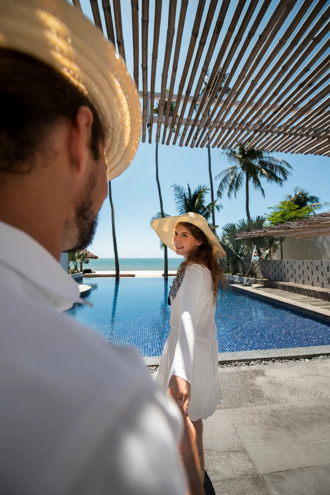 Pareja disfrutando una estancia junto a una piscina con vista al mar
