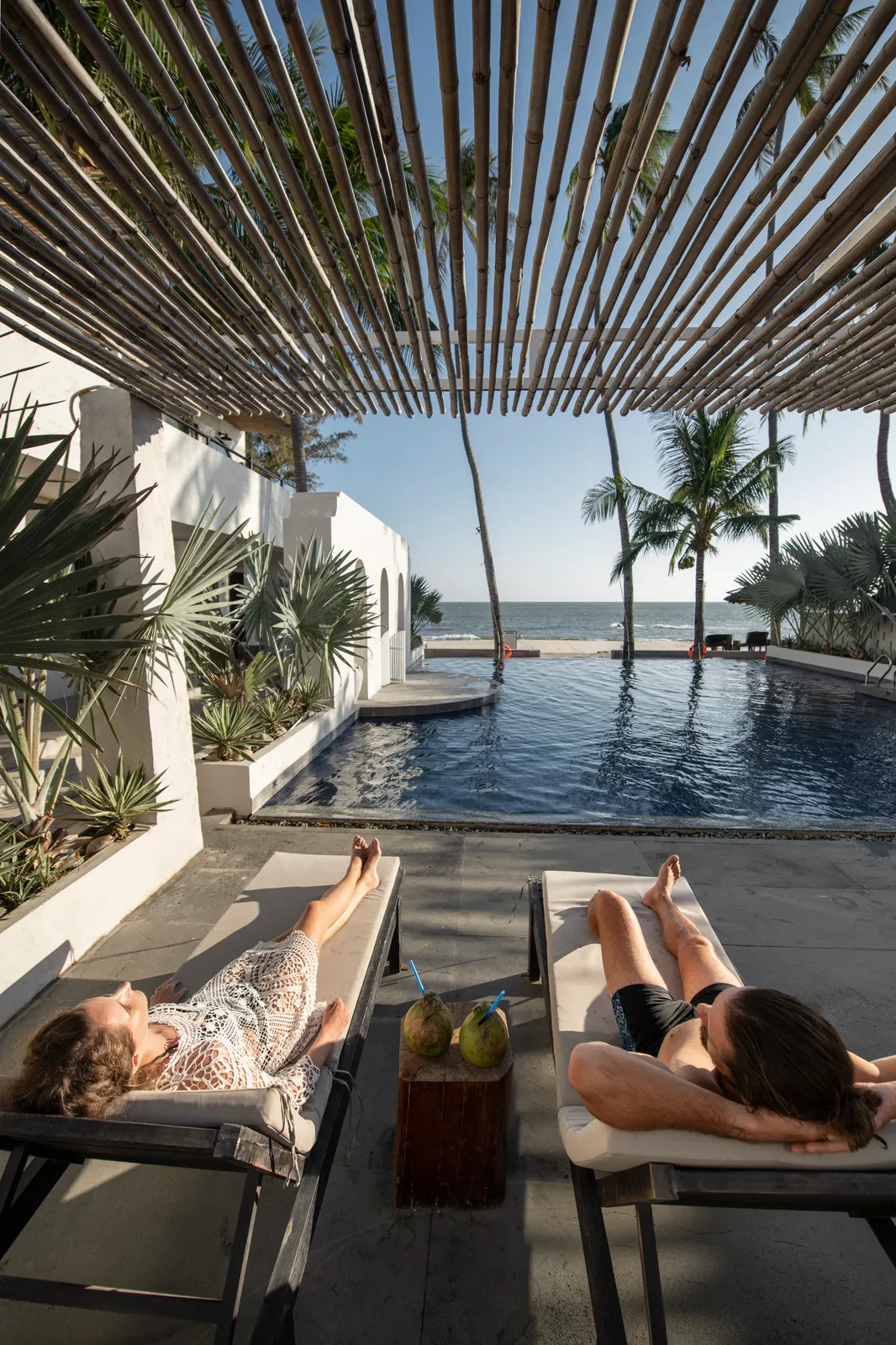 Pareja relajándose junto a una piscina durante unas vacaciones frente al mar