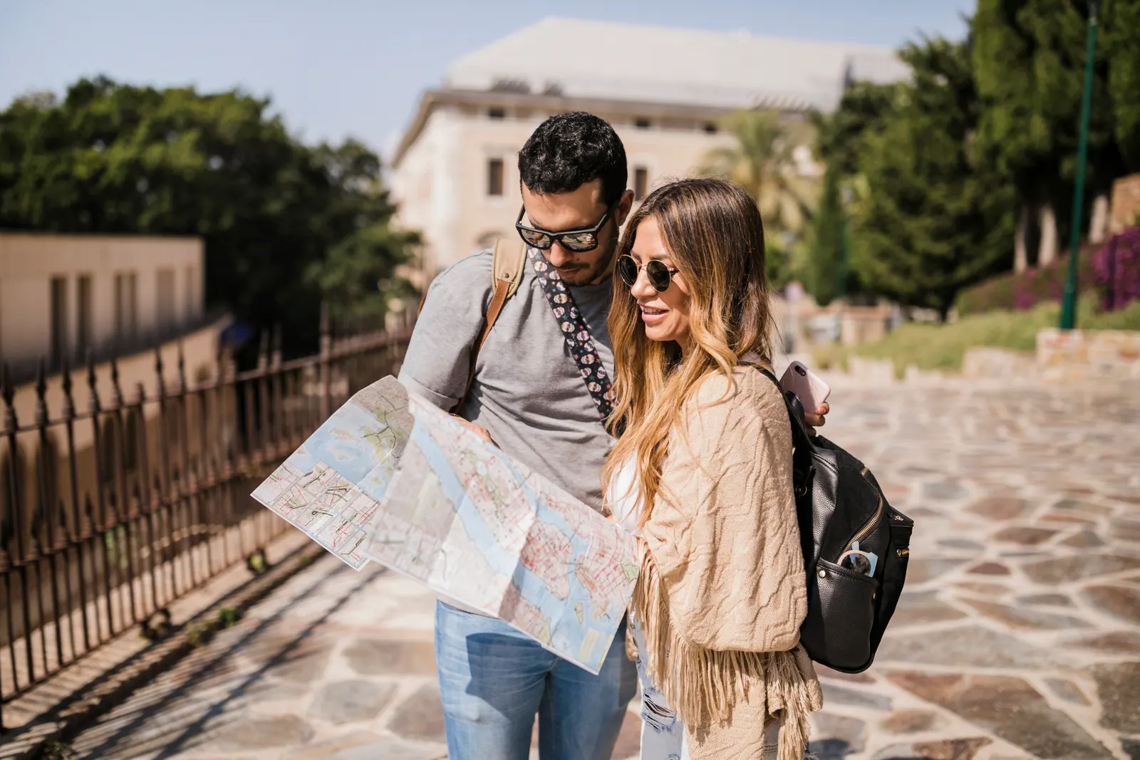 Pareja de turistas consultando un mapa mientras recorre una ciudad durante su viaje